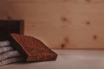 Pieces of dark rye bread and linen towel composed on a light wooden table