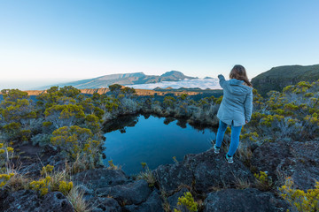 Naklejka premium Girl pointing the Piton des Neiges over a lake in Reunion Island