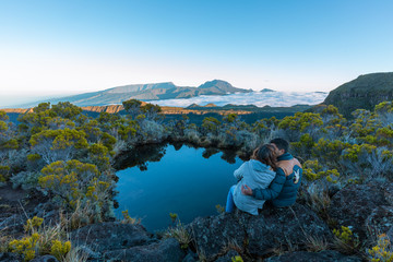 Couple kissing over a lake with a view of the Piton des Neiges in Reunion Island