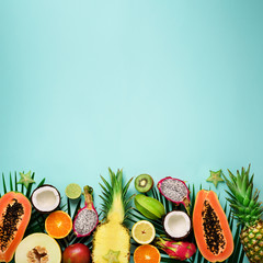 Exotic fruits and tropical palm leaves on pastel turquoise background - papaya, mango, pineapple,...