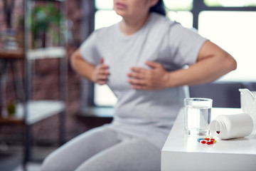 Period of contagiousness. Dull comfortless woman squeezing breast and coping with flu