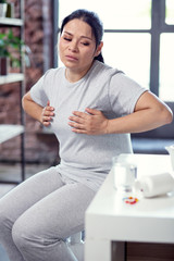 Risks from flu. Selective focus of glass of clean water and pills situating on table and woman touching breast