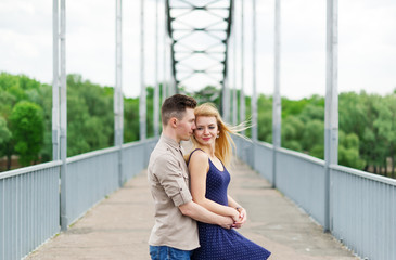 Young man is hugging with his loving girl on the city bridge