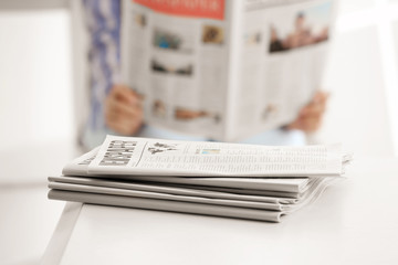 Heap of morning newspapers on white table