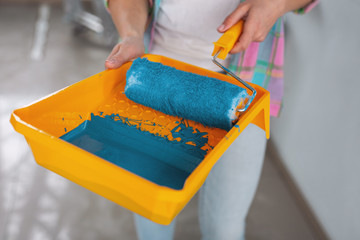 Great colour. Determined slim woman holding amazing heavenly blue paint and a roller