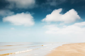 Sandy beach and blue sky with clouds.
