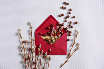Mail envelope with candies and pussy willow on light background
