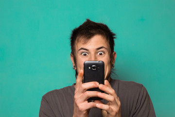 Guy making a selfie with funny faces. Guy taking pictures with his smartphone