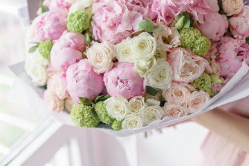 Young girl holding a beautiful spring bouquet. flower arrangement with hydrangea and peonies. Color light pink. The concept of a flower shop, a small family business