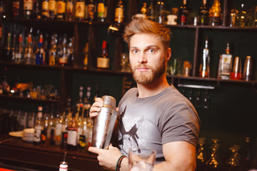 A stern bartender mixes a cocktail in a shaker