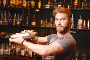 A stern bartender mixes a cocktail in a shaker