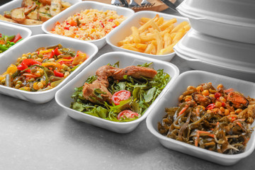 Foam plastic containers with delicious food on table