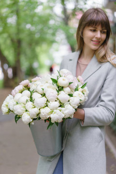 selective focus on flowers. Beautiful bouquet of white peonies in woomans hands . Floral composition, daylight. Wallpaper. Vertical photo