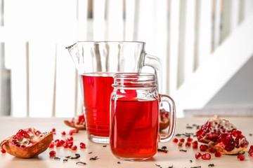 Red tea in mason jar and glass jug with pomegranate on table