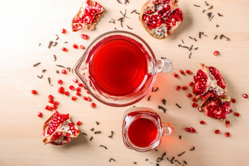 Red tea in mason jar and glass jug with pomegranate on light background, top view