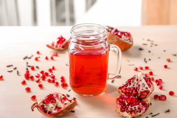 Red tea in mason jar with pomegranate on light background