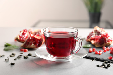 Glass with delicious red tea and pomegranate on table