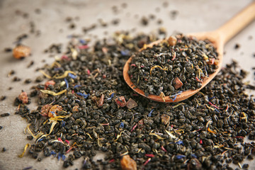 Dry tea and wooden spoon on grey background, closeup