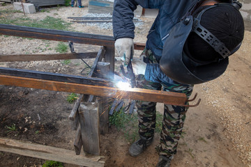 Welder welds metal at the construction site