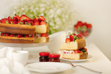 Homemade strawberry cake on a glass stand on the white background.