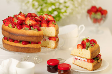Homemade strawberry cake on a glass stand on the white background.