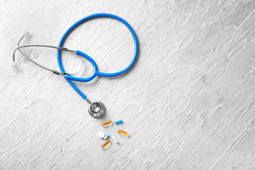 Fototapeta na wymiar Stethoscope with pills on wooden background. Health care concept