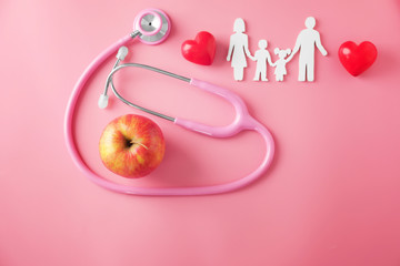 Family figure, apple and stethoscope on color background. Health care concept