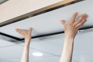 Woman hands removing white panel on ceiling