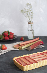 Scene with fresh baked rhubarb cake and fresh rhubarb and strawberries on the background