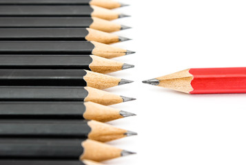 Obraz premium Red pencil standing out from crowd of plenty identical black fellows on white table. Leadership, uniqueness, independence, initiative, strategy, dissent, think different, business success concept