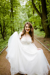 An smiling girl in a white dress walks along the path in the park