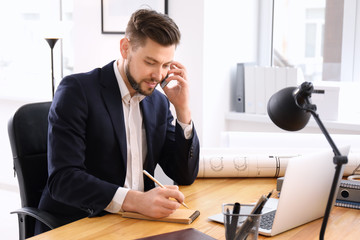 Businessman talking on phone while working in office