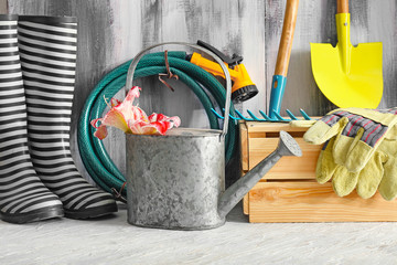 Rubber boots and gardening tools near wooden wall