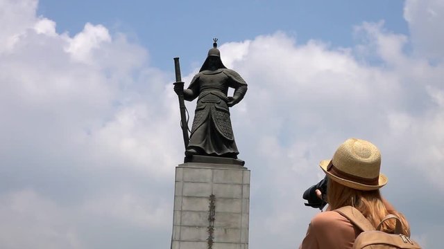 Young Female Traveler Taking Photo of Admiral Yi Sun-sin Monument with the title 'Everlasting Leader' on a sign at Gwanghwamun Square in Seoul, South Korea