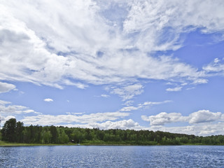 Summer landscape: blue lake on a Sunny day and sky with feathery clouds