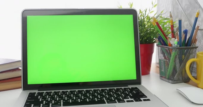 Dolly in of Laptop with green screen. Dark office.  Perfect to put your own image or video.Green screen of technology being used. Chroma Key laptop