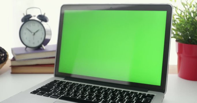 4K : A laptop computer with a key green screen set on work office table. Dolly in
