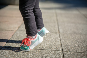 Closeup of little girl legs with sneakers and black leggins training outdoors