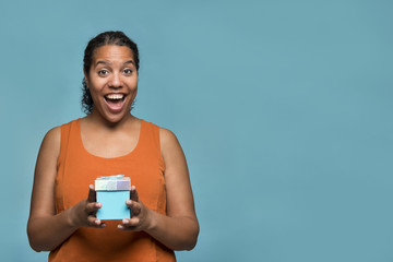 Young pretty black woman getting holding a blue gift box on a blue background