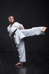  A girl in a white kimono with a black belt on a dark background