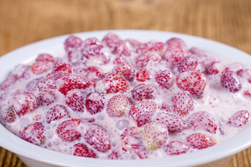 Fresh, ripe, forest strawberries with sour cream and honey in white plate, wild berry. Red strawberries background