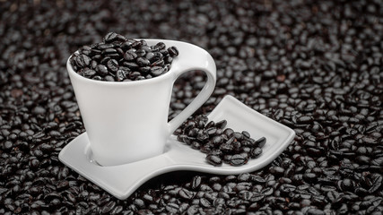 white cup of coffee with coffee beans on a background of coffee beans