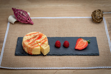 Delicious dessert cheesecake dish with strawberries and raspberry. Wooden table and black pizza table