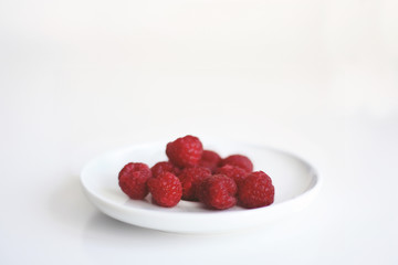 Himbeeren in einer weissen Schale vor weißem Hintergrund