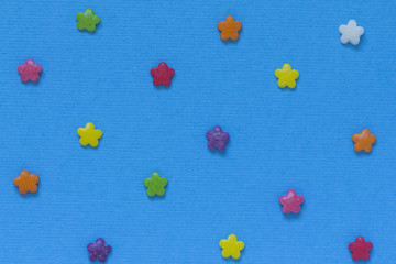 Multicolored candy in the form of flowers on a blue background.