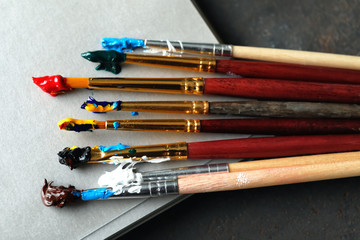 Notebook with paint brushes on table, closeup