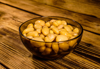 White marinated haricot beans in glass bowl on a wooden table