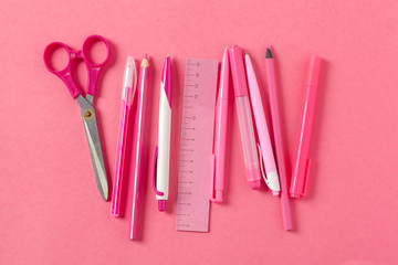 On a pink background, school accessories and a pen, colored pencils