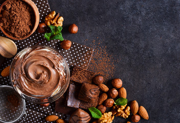 Black food background with cocoa, nuts and chocolate paste. top view