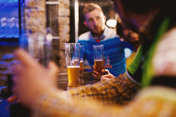 Several football fans are drinking beer and sitting by the bar.